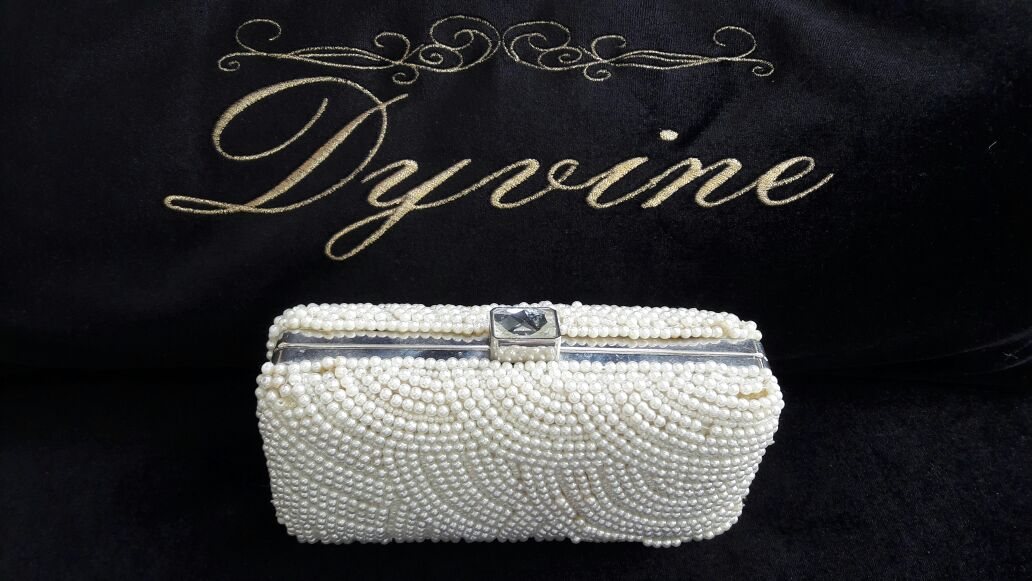 Clutch de pérolas sobre veludo preto bordado com a marca Dyvine