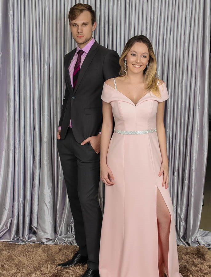 Ensaio de campanha: mulher loira de vestido longo rosé com fenda ao lado de homem de terno grafite e gravata vinho