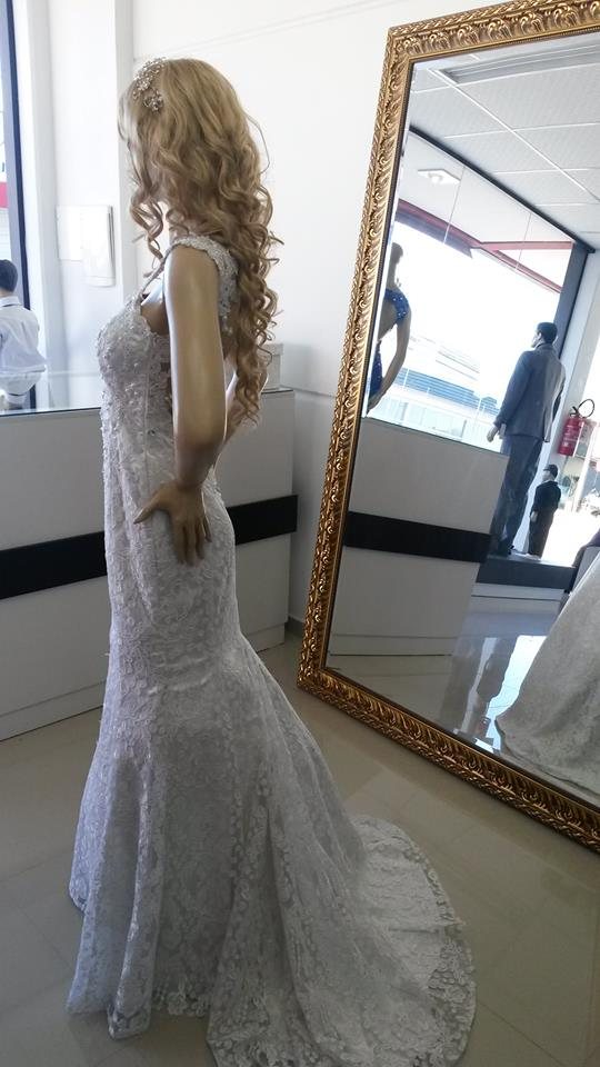 Vestido de noiva sereia de renda em manequim, ao lado de um espelho