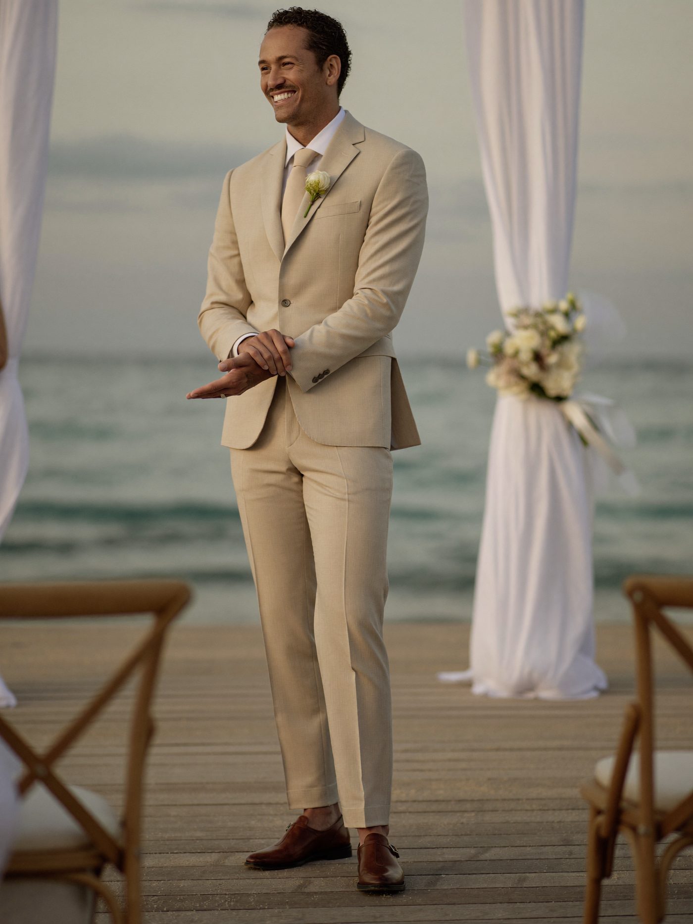 Noivo de terno bege em um casamento na praia